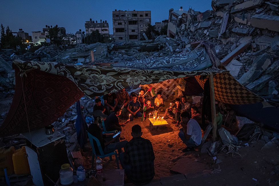 Палестинские дети собираются со свечами во время хрупкого прекращения огня в Бейт-Лахии, Газа, 25 мая 2021 года, после акции протеста детей по соседству против нападений на Газу.