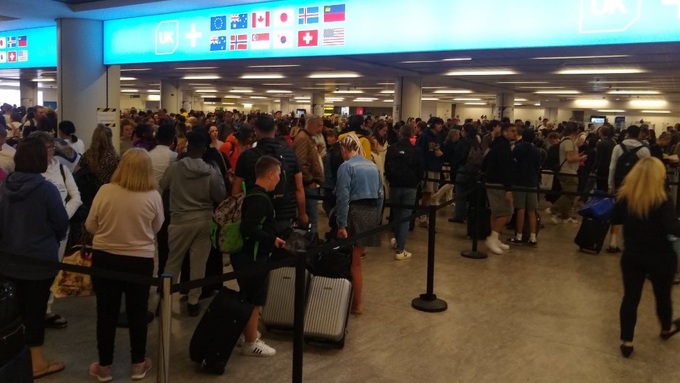 A queue of passengers waiting at passport control at Gatwick Airport