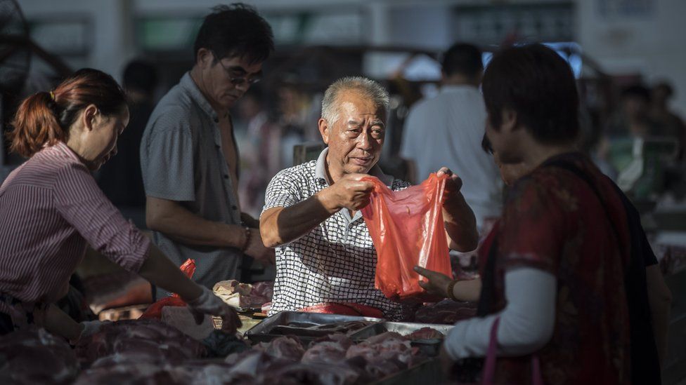 A butcher sells pork at a market in China