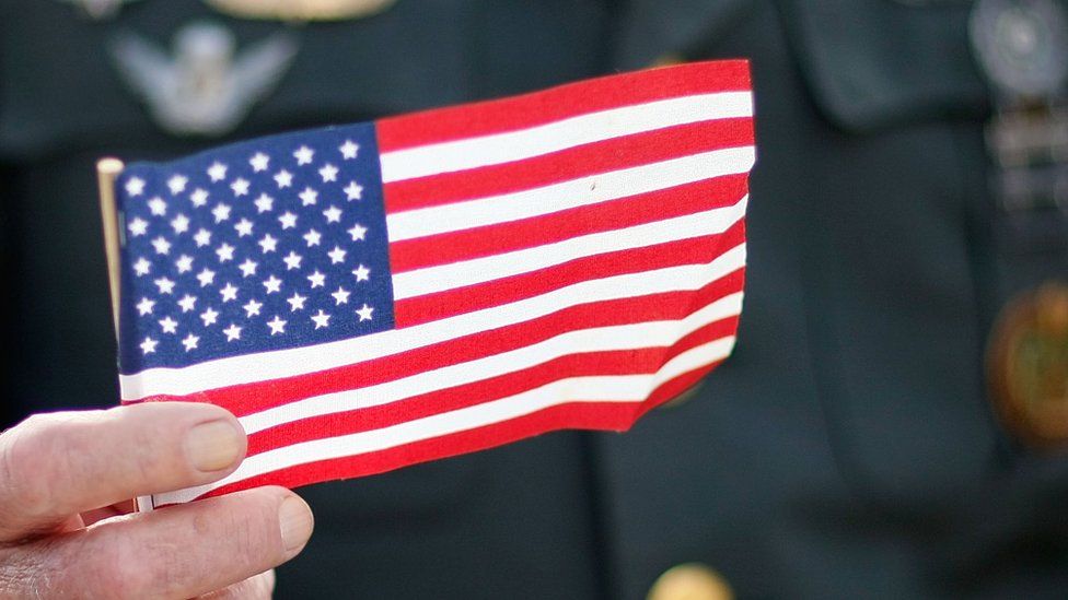 An American war veteran holds a small US flag