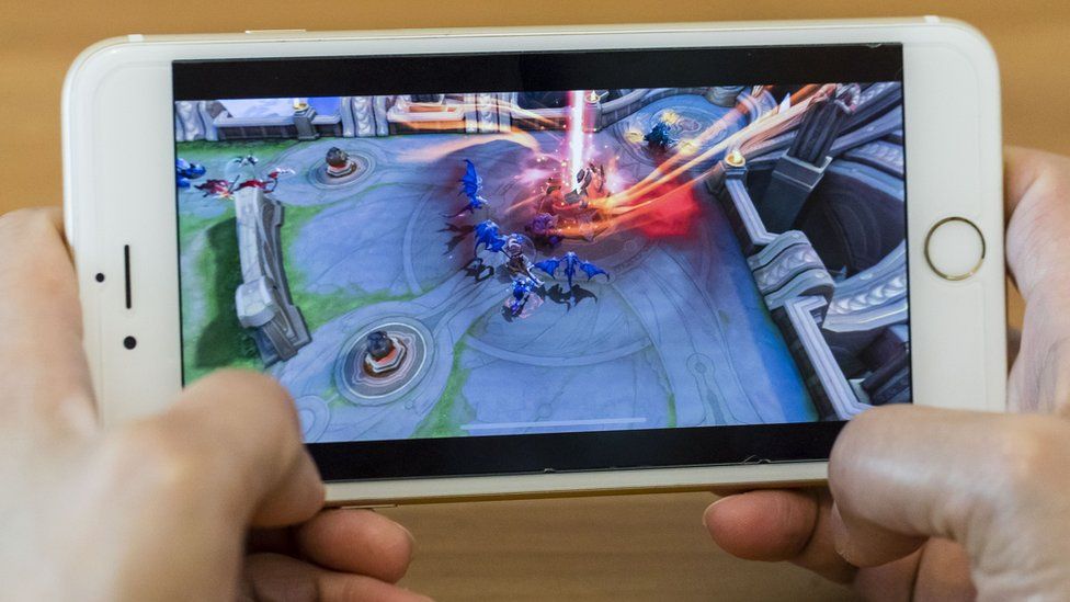 One of Tencent's popular mobile games runs on an iPhone being held by a person
