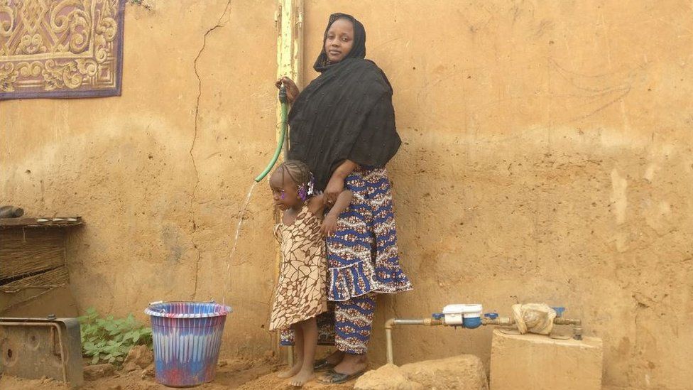 Woman and child filling bucket with water