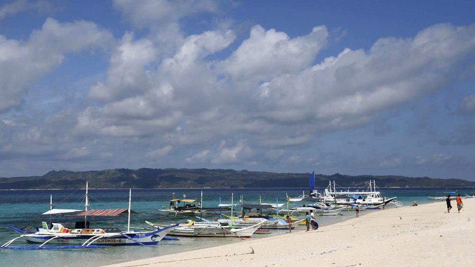Traditional boats line up the shore in a secluded beach on the island of Boracay