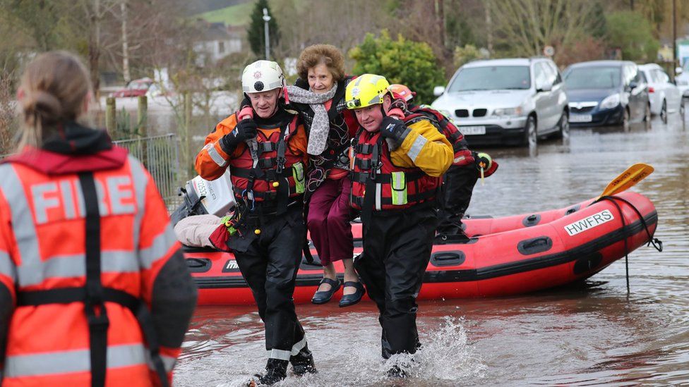 A woman is lifted to safety by rescue workers