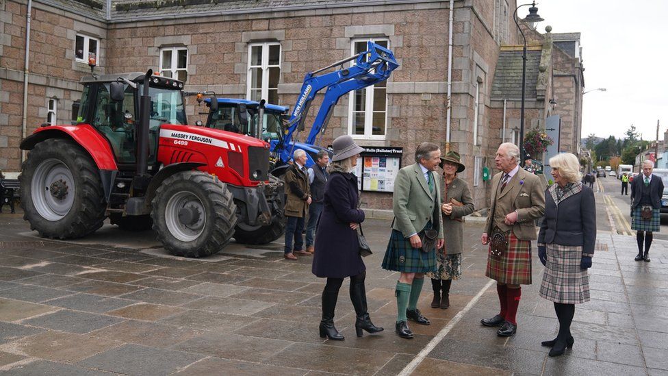 The King and Queen Consort with tractors in background
