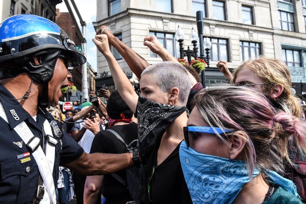 A group of protesters hold their fists towards a police officer.