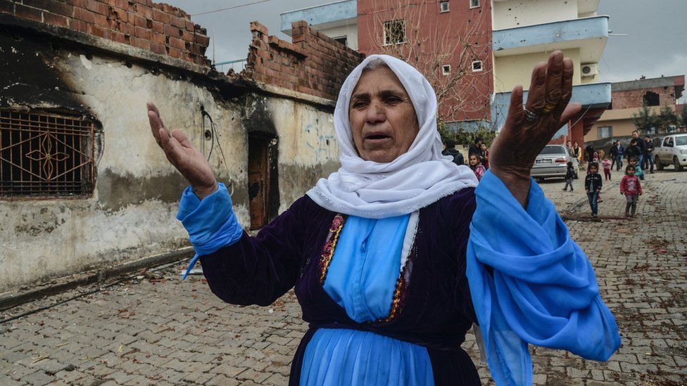 A woman outside her damaged house during fighting between government troops and separatist Kurdistan Workers' Party (PKK) fighters, in the Kurdish town of Silopi, in south-eastern Turkey