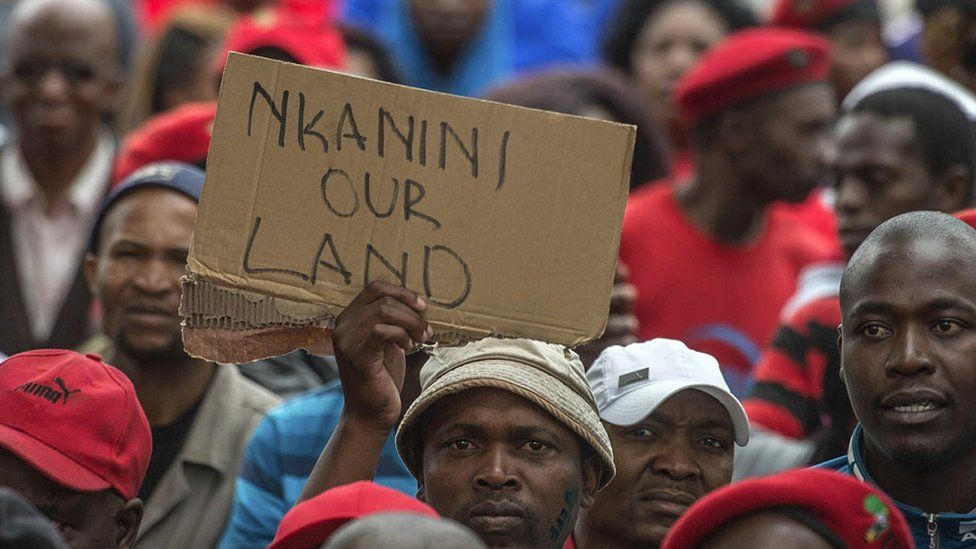 South African opposition protest in 2016 with someone holding up a sign reading "Nkanini our land".