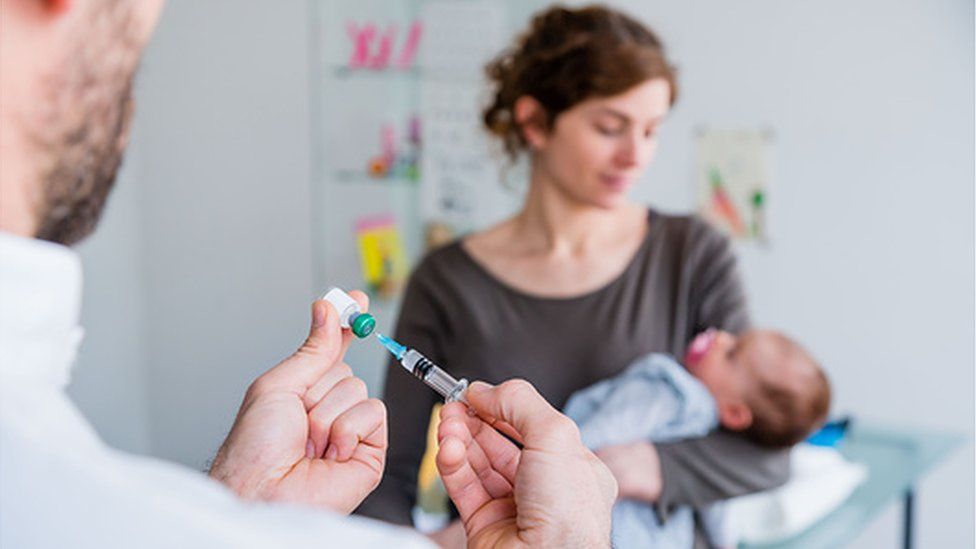 Doctor holds syringe near baby
