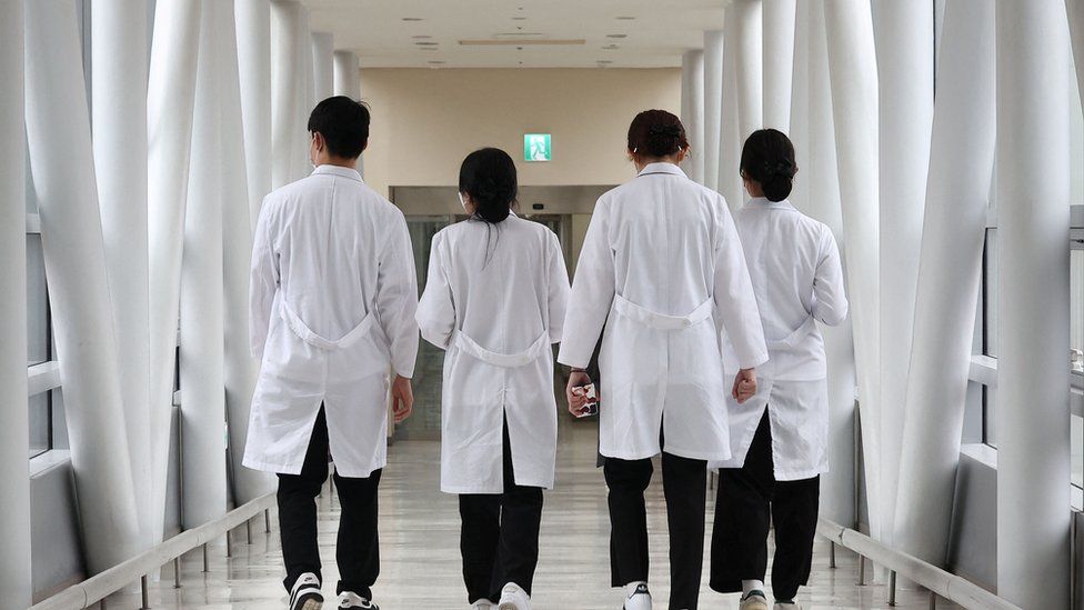 A group of doctors walk with their backs turned down a hospital corridor in Seoul