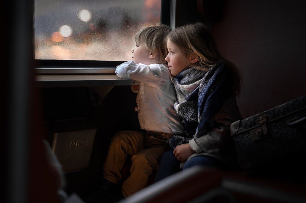 Two children looking out of a window