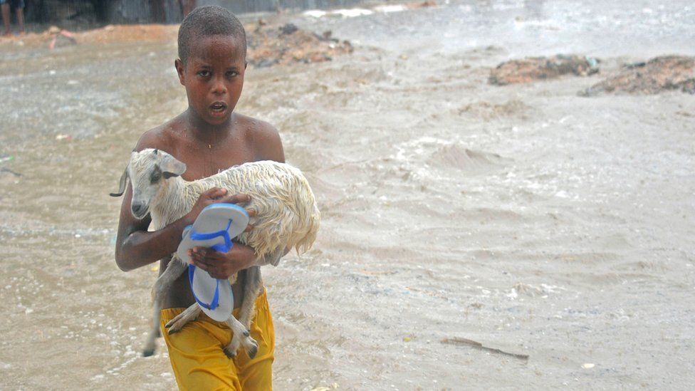 A young boy carries a goat across a flooded street in Mogadishu, 3 May 2016
