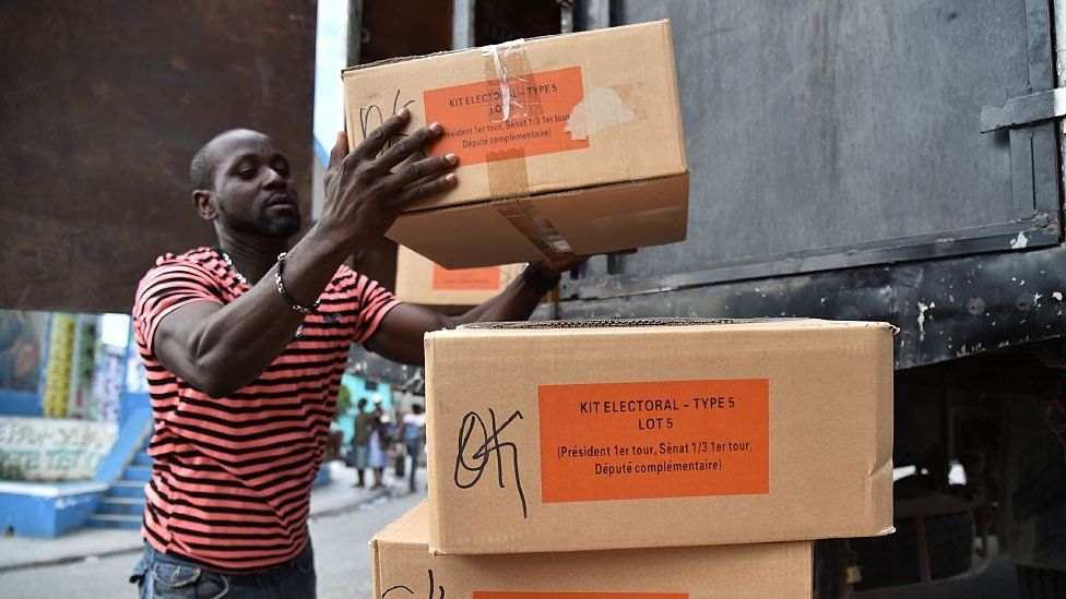 A worker unloads a box with electoral materials delivered by the Provisional Electoral Council (CEP) one day before of the general elections at a polling station in Port-au-Prince, on November 19, 2016.