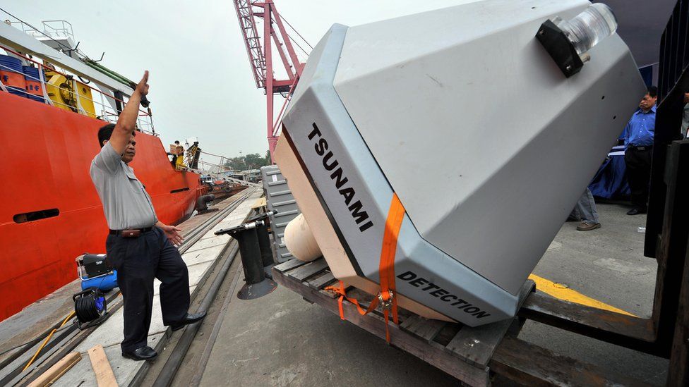 Workers unload a Tsunami Buoy, a device to detect early tsunami warnings, in Jakarta