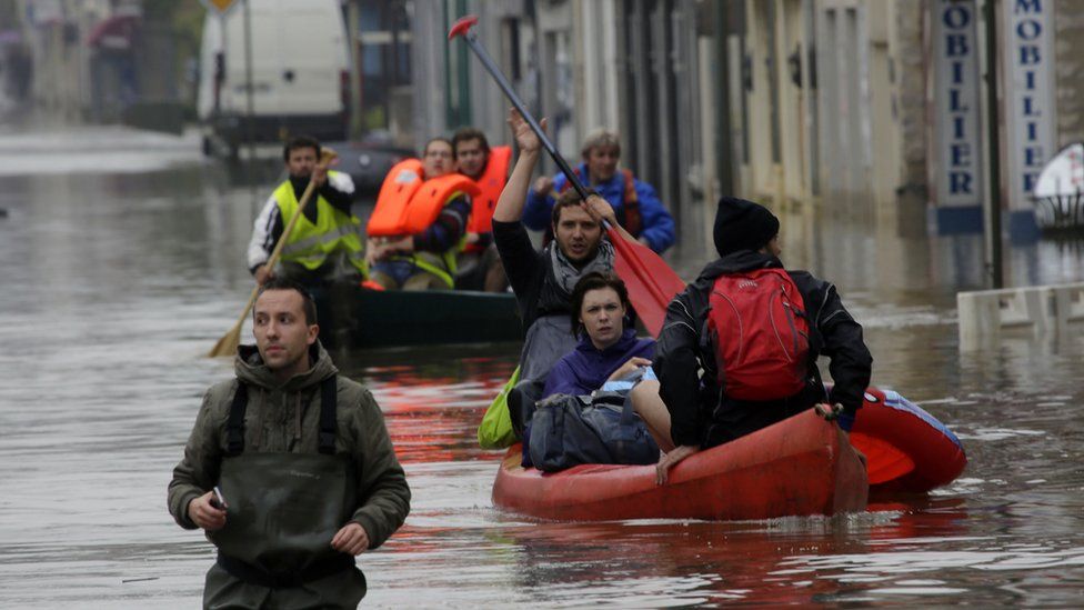 People in Nemours, France, paddle through flooded streets