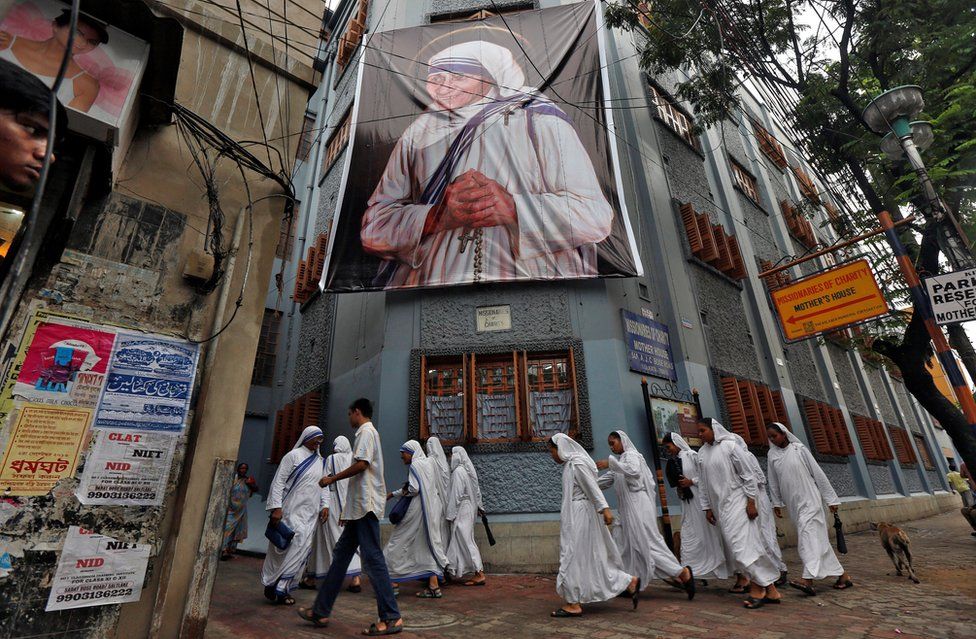 Nuns belonging to the global Missionaries of Charity, walk past a large banner of Mother Teresa ahead of her canonisation ceremony, in Kolkata, India