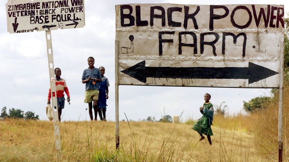 Schoolchildren pass the entrance to an occupied farm outside Harare, Zimbabwe - 2000