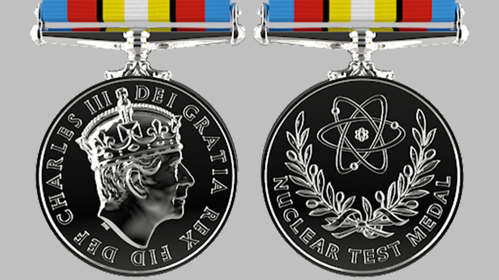 picture of medal. It is silver and round. One side features an image of King Charles, and the other shows an atom and olive branches, with the words "Nuclear Test Medal"