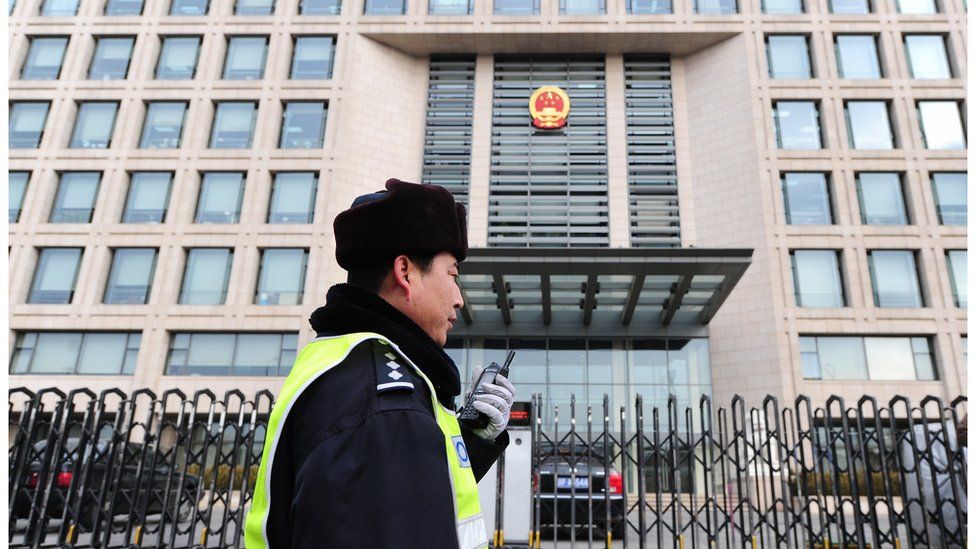 A policeman speaks into his walkie-talkie while on patrol outside the off-limits courthouse which upheld the 11-year jail term for leading Chinese dissident Liu Xiaobo. 11 Feb 2010, Beijing.
