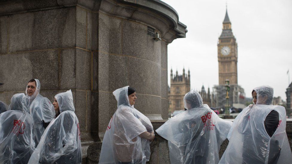 Tourists shelter from the rain on Westminster Bridge