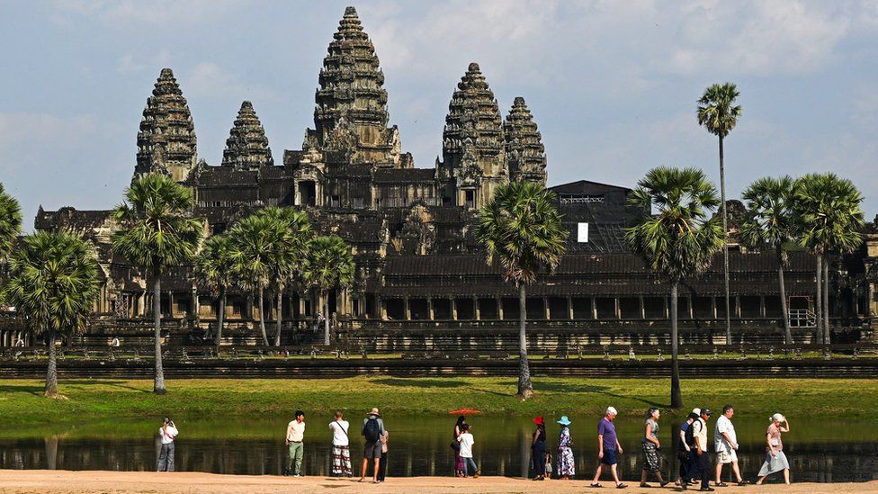 Touristen gehen vor der Tempelanlage von Angkor Wat spazieren