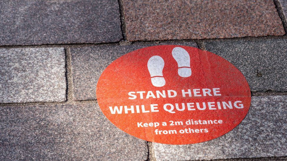 A sign on the floor about social distancing by two metres
