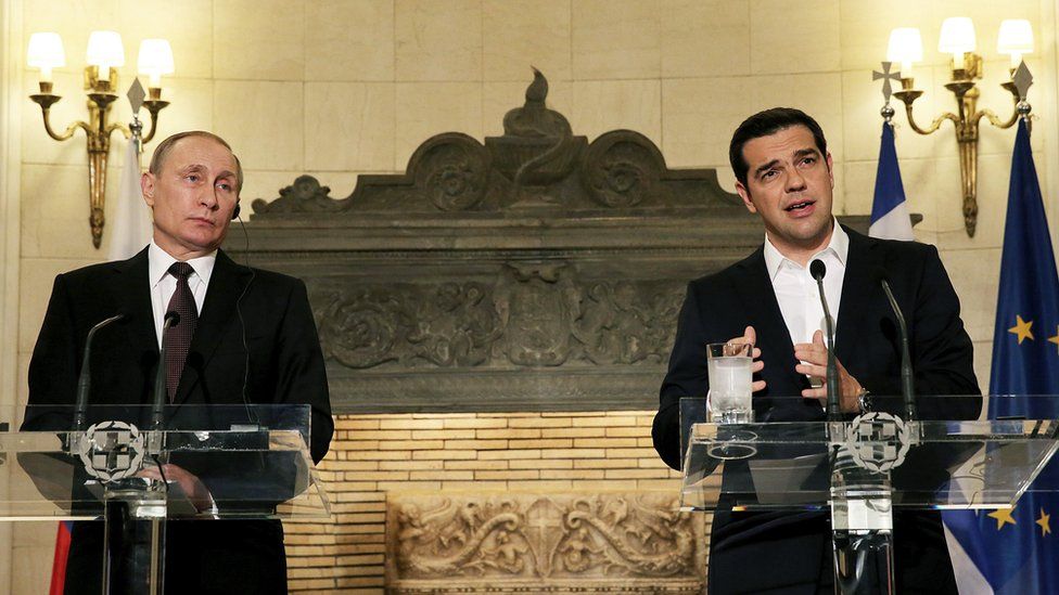 Alexis Tsipras and Vladimir Putin speaking from lecterns at a press conference