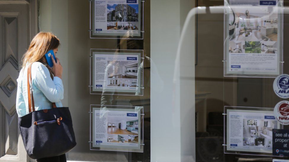 Woman looks in estate agent window