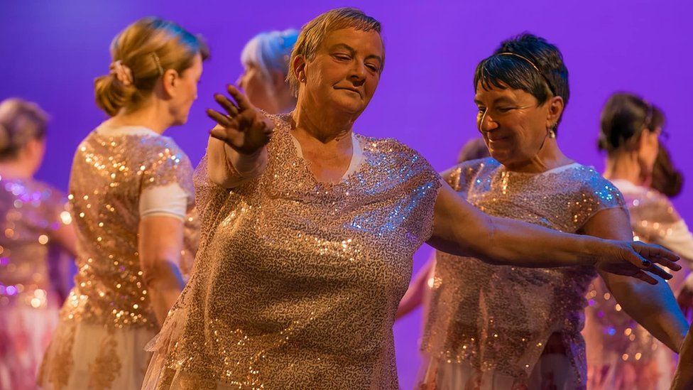 Women in pink sparkly tops dance