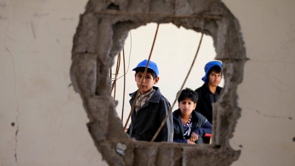Boys look through a hole in a wall in their school in Sanaa, Yemen, reportedly caused by a Saudi-led coalition air strike (5 October 2016)