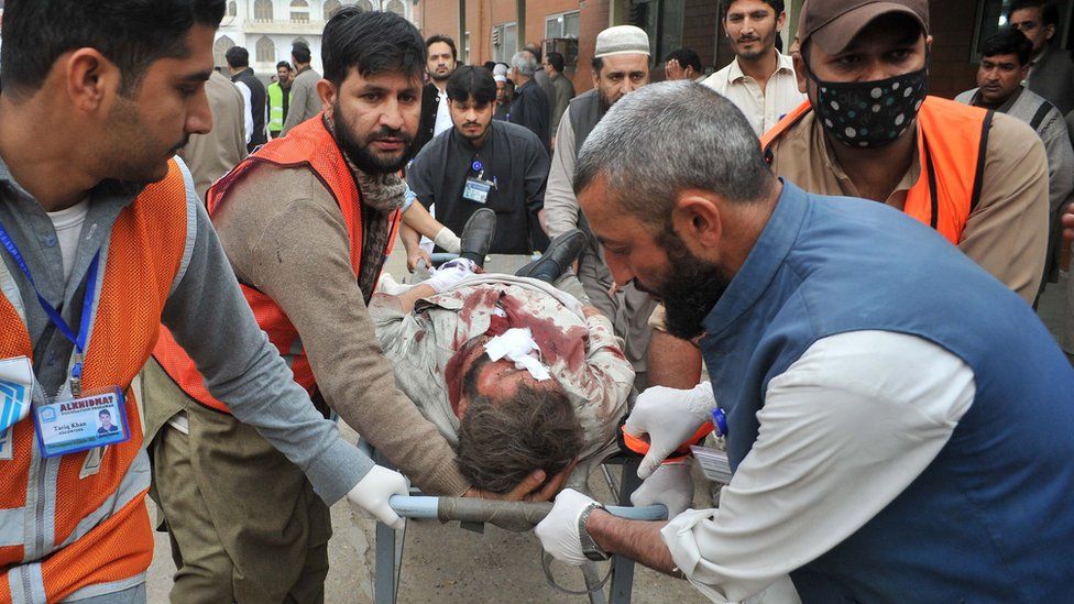 Pakistani volunteers move an injured blast victim to hospital