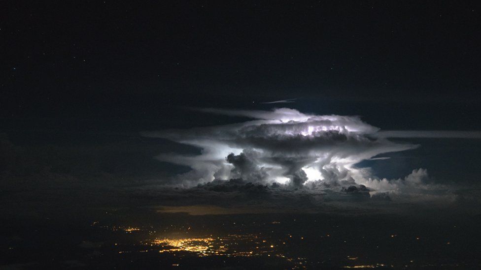 Nubes blancas en un cielo oscuro sobre las luces de una ciudad