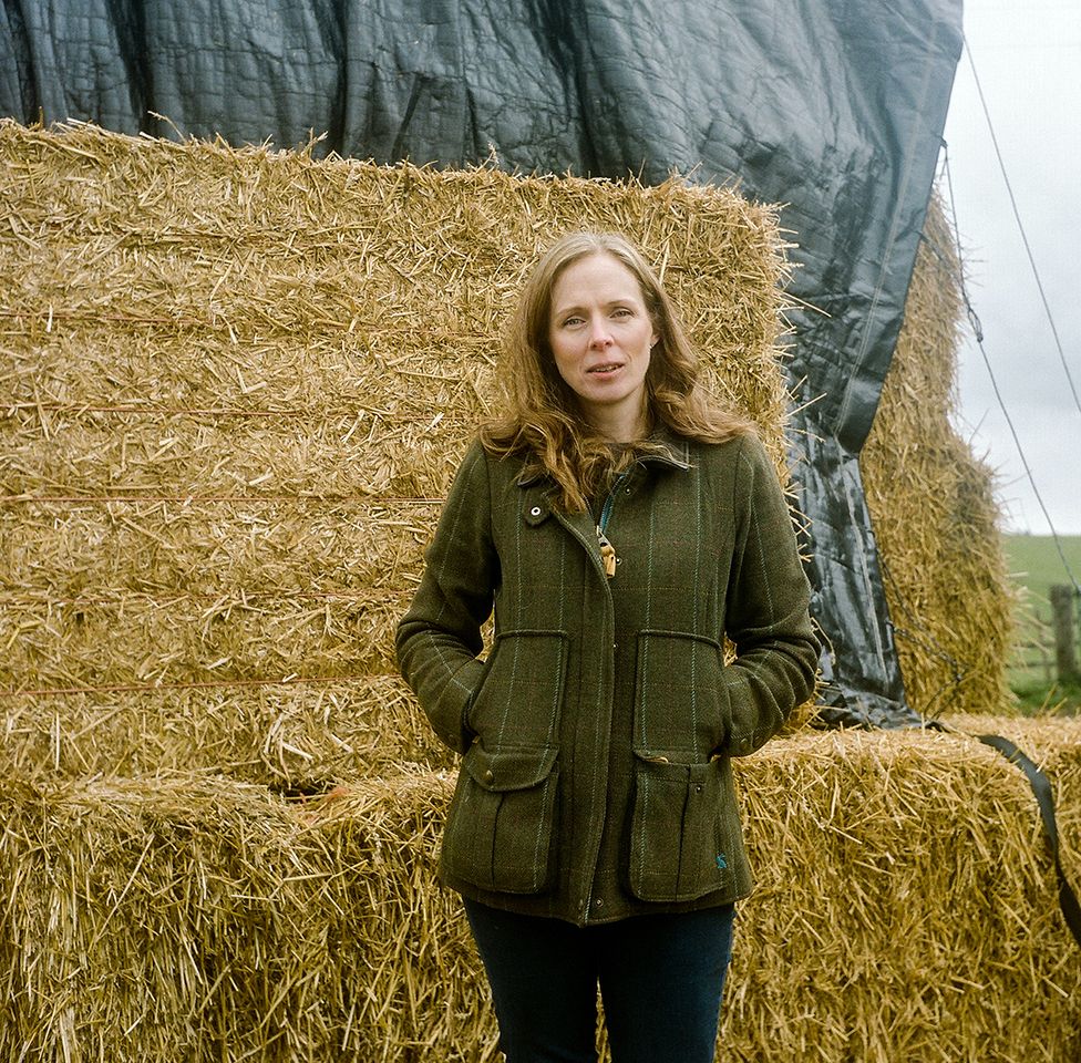 Debbie, a farmer's wife, stands next hay bales on her farm near Otterburn in Northumberland