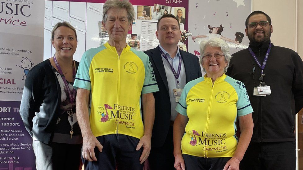 Ted and Denise Pearson are congratulated by Ciaran O'Donnell, Head of Wolverhampton Music Service (centre) and colleagues after completing their epic fundraising bike ride from John O’Groats to Land’s End.