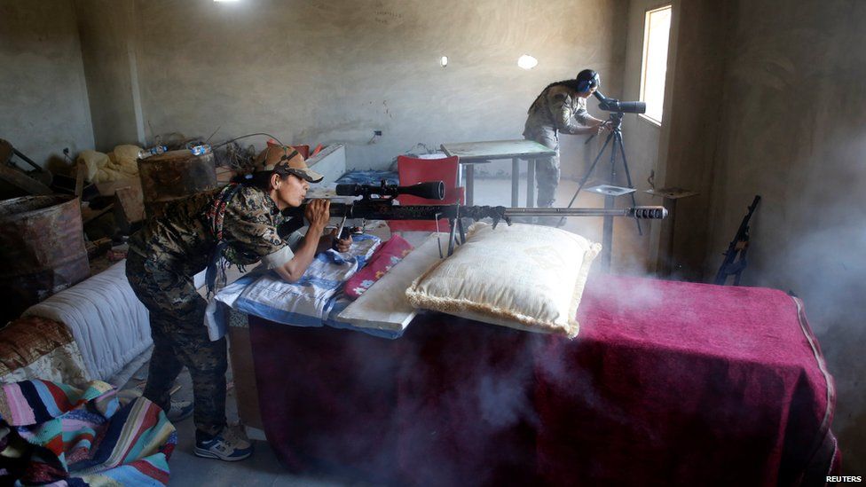 Kurdish fighters from the People's Protection Units (YPG) talk in a sniper position located in a house in Raqqa