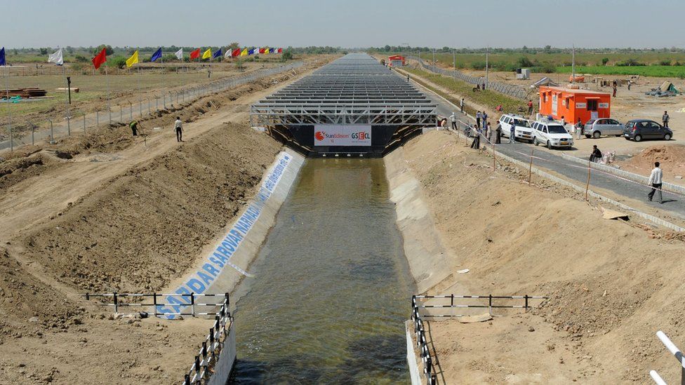 A solar farm nears completion over a levee in Gujarat