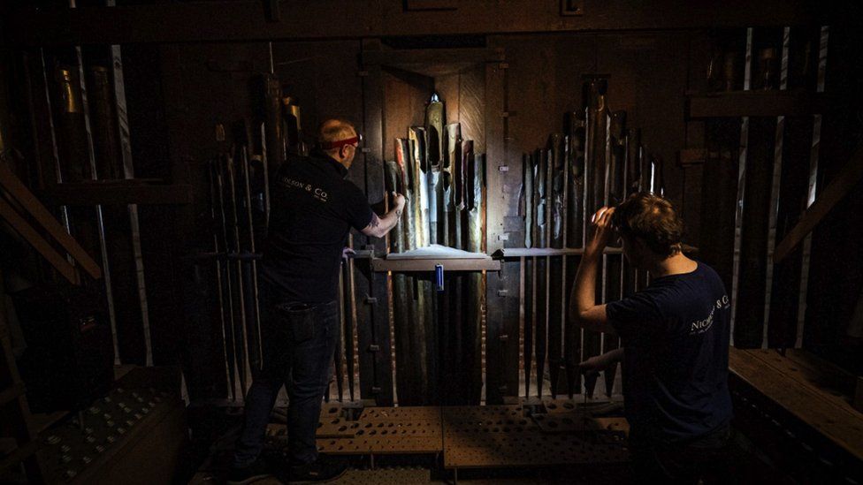 Image of two men working on the organ in Gloucester Cathedral.