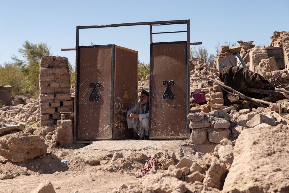A man sitting at a doorway - the only remaining piece of what used to be his home in Siah Ab