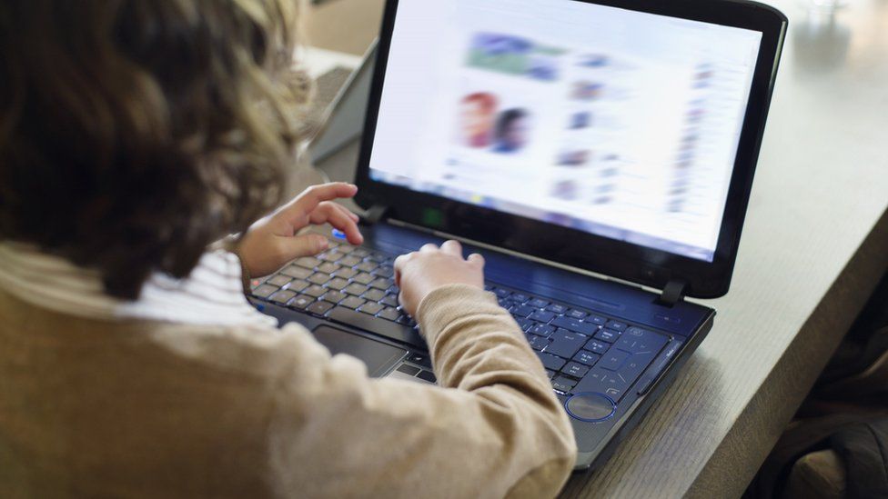 Child looking at computer screen with screen blurred out