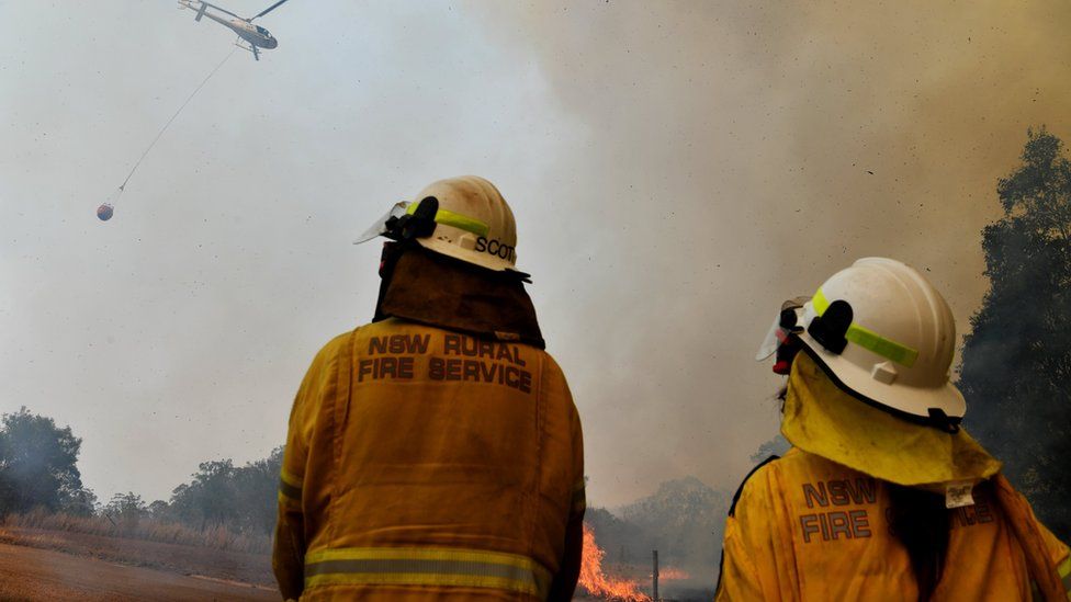 Firefighters watch as helicopter surveys a spot fire in Hillside New South Wales on 13 November