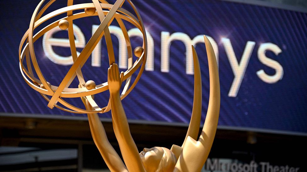 Giant Emmy Awards trophy in front of a screen saying "Emmys"