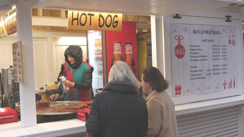 A hotdog vendor displaying prices in both euros and kunas