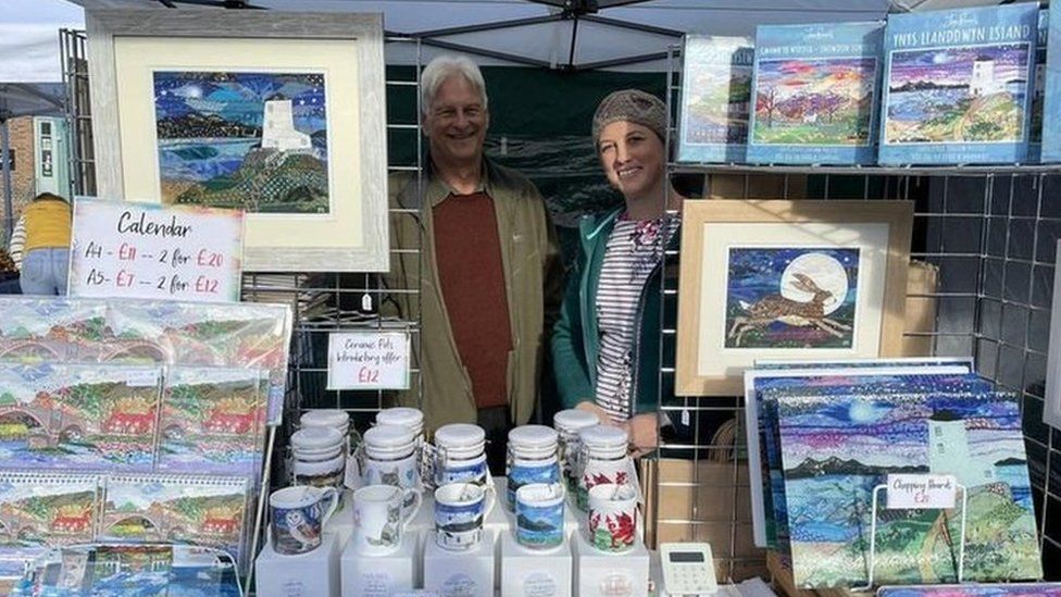 Shaun Russell and his daughter Josie on a stall at a fair surrounded by Josie's artwork