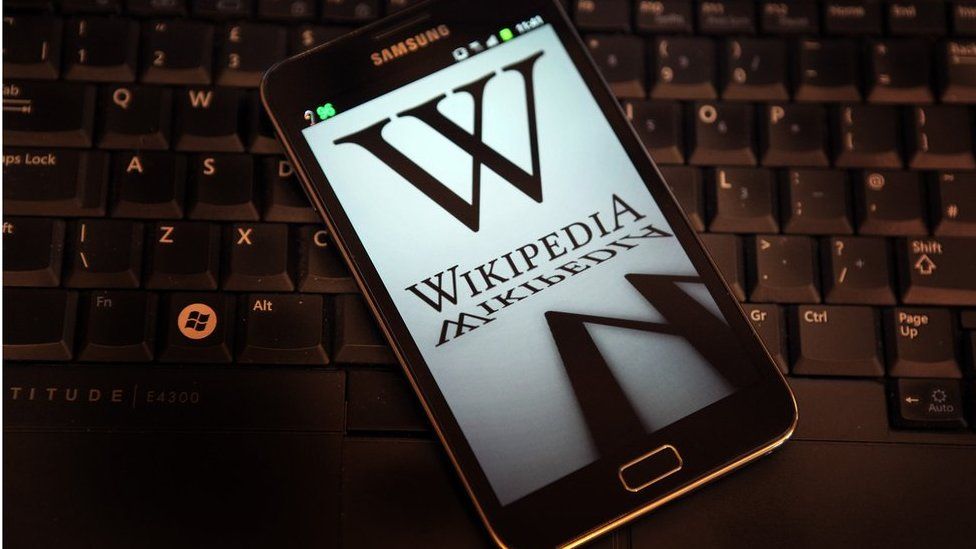 A mobile device shows Wikipedia's front page displaying a darkened logo on 18 January, 2012