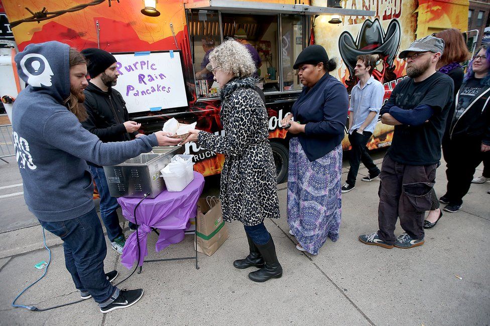 Harry Awe, left, and Josh Combs, hand out free "Purple Rain Pancakes" outside the First Avenue club in Minneapolis, 22 April