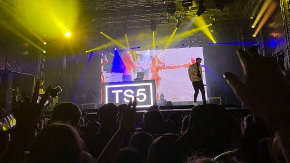 Performers at a music festival with floodlights shining on them