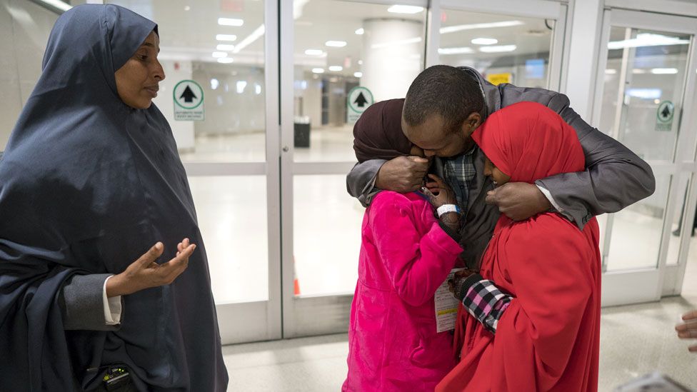 Ismail Issack, father of Miski Shalle, 11, and Muzamil Shalle, 14, embraces his children at JFK airport