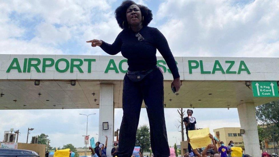 A demonstrator stands atop a vehicle and shouts slogans as others carry banners while blocking a road leading to the airport, during a protest over alleged police brutality, in Lagos, Nigeria October 12, 2020.