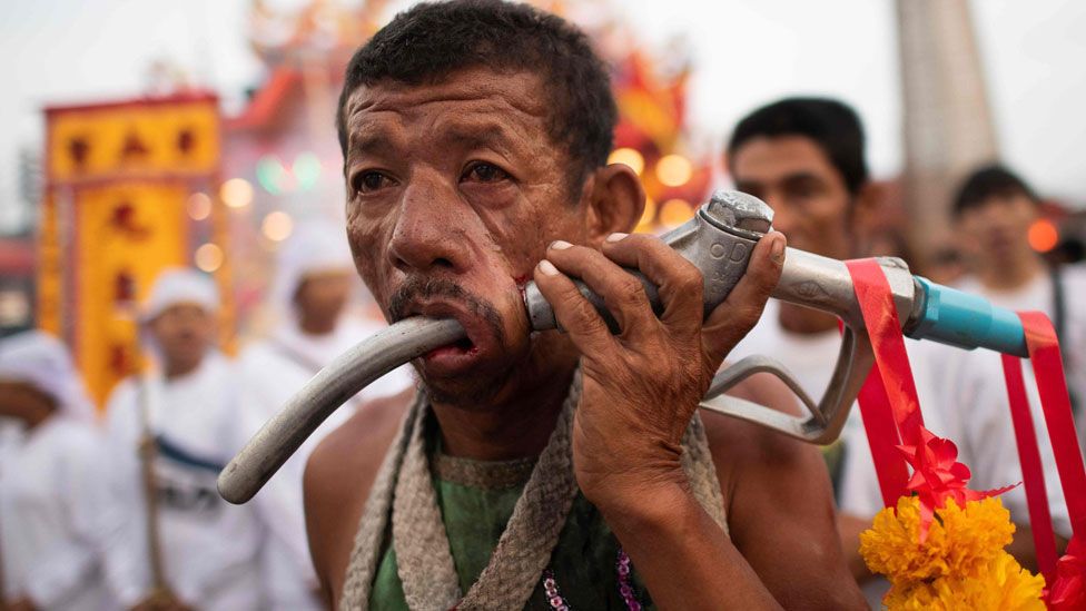 A devotee has a gas-pump nozzel pierced through his cheek