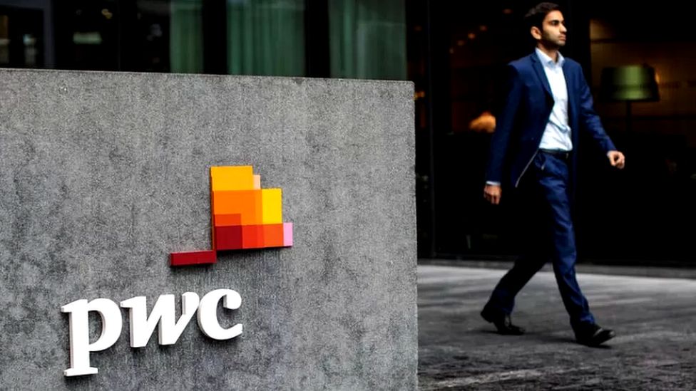 Man walks past PwC sign